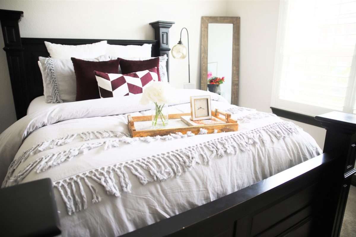 feminine guestroom, girl guestroom, guestroom, boutique style guest room, colorful guestroom, accent chair in guest room, black bed, wooden bed, floor mirror, textured bedding, guest bedroom decor